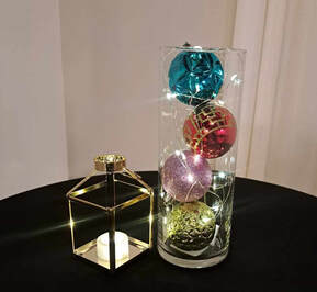 wedding reception or event centerpiece with cylinder vase with ornaments and fairy lights and gold mini lantern